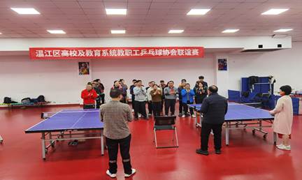 A group of people standing in a room with ping pong tablesDescription automatically generated