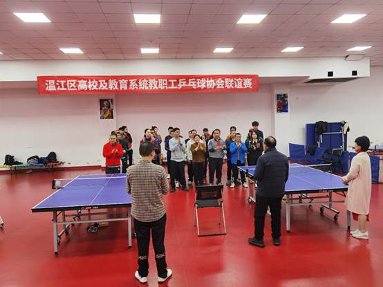 A group of people standing in a room with ping pong tablesDescription automatically generated